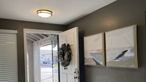 A hallway with a white door, a blue patterned rug, and two framed artworks on the wall. - Spacious Home, Private Pool, minutes to Spring Training, and Cardinal Stadium (Peoria)