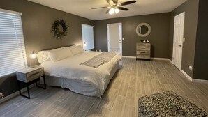 A bedroom with a bed, bedside table, dresser, and a ceiling fan. - Spacious Home, Private Pool, minutes to Spring Training, and Cardinal Stadium (Peoria)