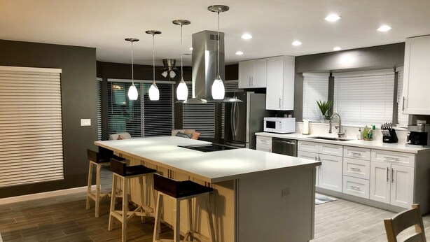 A modern kitchen with a central island, bar stools, stainless steel appliances, and pendant lighting. - Spacious Home, Private Pool, minutes to Spring Training, and Cardinal Stadium (Peoria)