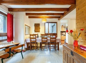 Un espace repas avec des tables et des chaises en bois, une fenêtre avec des volets et un plafond en bois.
