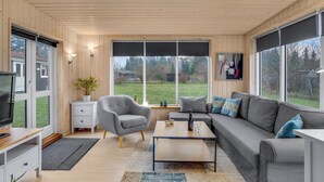 Ett modernt vardagsrum med en grå soffa, ett litet soffbord, en grå fåtölj och en tv som står på ett träskåp.