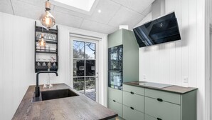 A modern kitchen with a wooden countertop, a built-in sink, a green cabinet, and a flat-screen TV mounted on the wall. - Amazing home in Nexø with kitchen (Nexø)