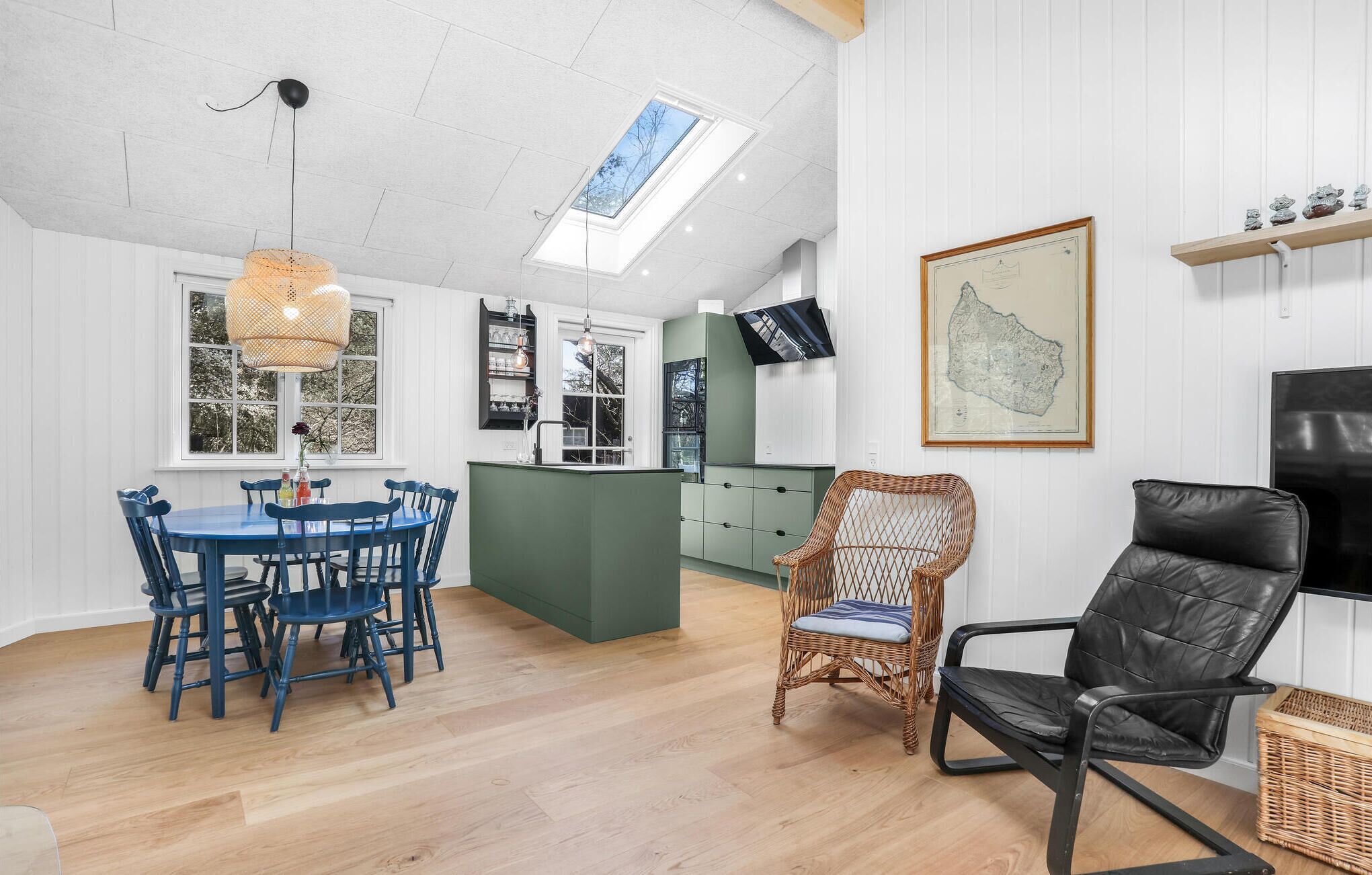 A modern kitchen with a dining area, a television, and a map on the wall.