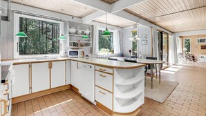 Una cucina moderna con mobili bianchi, un piano di lavoro in legno e lampade a sospensione verdi.