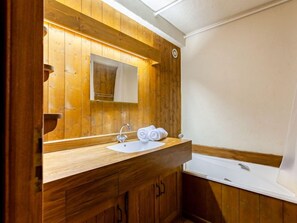 Une salle de bain en bois avec un lavabo, un miroir et une douche.
