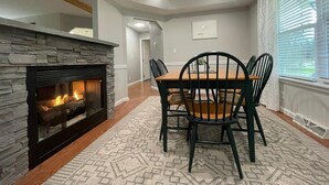 A dining area with a stone fireplace, a wooden table, and four chairs. - Tranquil, Stylish Elk Mountain Home with Lake Access (Union Dale)