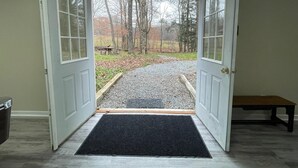 A doorway leading to a gravel path with a bench and trees in the background. - Tranquil, Stylish Elk Mountain Home with Lake Access (Union Dale)