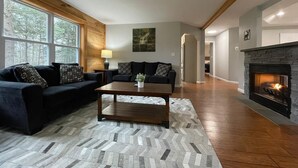A living room with a fireplace, a sofa set, and a herringbone-patterned rug. - Tranquil, Stylish Elk Mountain Home with Lake Access (Union Dale)
