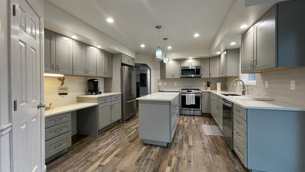 A modern kitchen with grey cabinets, stainless steel appliances, and a central island. - Tranquil, Stylish Elk Mountain Home with Lake Access (Union Dale)
