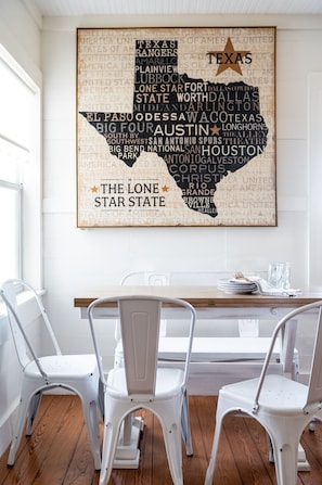 Enjoy meals in this dining area with a wooden table and comfortable chairs, featuring a large map of Texas above.