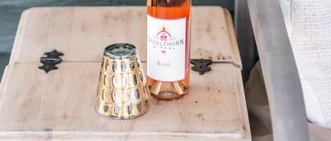 A white chest of drawers with a bottle of wine and a glass on top.