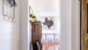 Un couloir avec un plancher en bois, un mur blanc orné d’une carte du Texas et un meuble en bois.