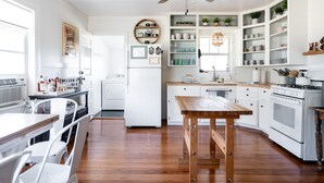 Une cuisine avec des meubles blancs, une table en bois et un ventilateur de plafond.