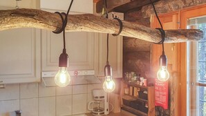 A rustic kitchen with exposed wooden beams, a coffee maker, and hanging light fixtures.
