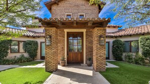 A two-story house with a brick facade, a wooden front door, and a tiled roof. - Private Estate - Enough amenities to keep kids and adults having a great time (Bermuda Dunes)
