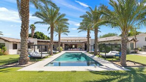 A pool with palm trees, a building with a tiled roof, and a well-maintained lawn. - Private Estate - Enough amenities to keep kids and adults having a great time (Bermuda Dunes)