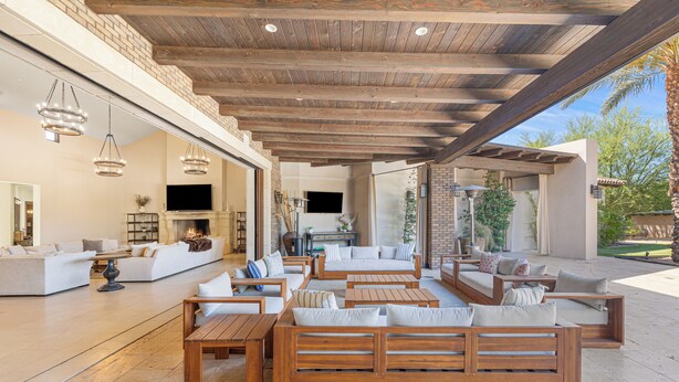 An outdoor living area with wooden furniture, a flat-screen TV, and a brick wall. - Private Estate - Enough amenities to keep kids and adults having a great time (Bermuda Dunes)