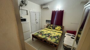 A bedroom with a bed, a bedside table, a wardrobe, an air conditioning unit, and a ceiling fan. - Studio Vacances Martinique 3 ilets (Trois ilets)
