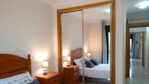 Een hotelkamer met een grote spiegel, een houten bed, nachtkastjes met lampen en een kledingkast.