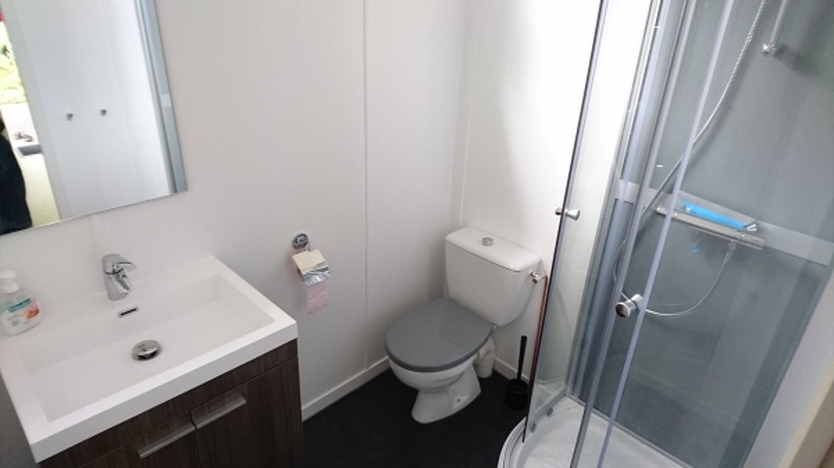 A bathroom with a white sink, toilet, and glass shower enclosure.