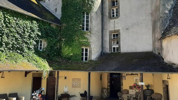 A courtyard with a stone tower, ivy-covered walls, and a seating area with outdoor furniture.
