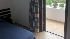 Un dormitorio con cama, cortina y puerta corrediza de vidrio que da a un balcón.