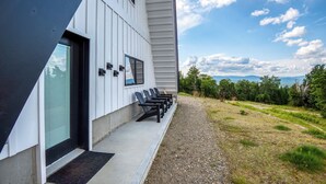 Un bâtiment moderne doté d’un porche et d’un espace extérieur aménagé pour s’asseoir.