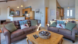 Ein gemütliches Wohnzimmer mit zwei Sofas, einem Couchtisch und einer Küche im Hintergrund.