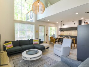 Un salon moderne avec un canapé d’angle, une table basse ronde et un coin repas comprenant une table et des chaises.