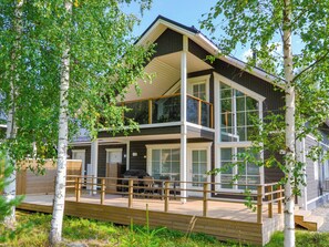 Une maison moderne à deux étages, dotée d’une terrasse et de grandes fenêtres.