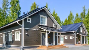 Eine zweistöckige Lodge mit überdachter Veranda und einem separaten Blockhaus.