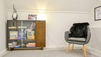 A room with a wooden cabinet containing books and a plush chair with a fur throw.