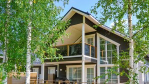 Ein modernes, zweistöckiges Haus mit Terrasse und Sitzgelegenheit im Freien.