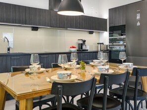 A modern kitchen with dark cabinetry, a stainless steel refrigerator, and a dining area set for a meal.