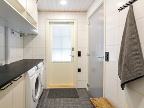 Une petite buanderie équipée d’un lave-linge, d’un étendoir et d’une serviette accrochée au mur.