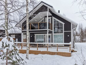 Une maison moderne à deux étages, dotée d’une grande terrasse et d’un espace extérieur couvert.