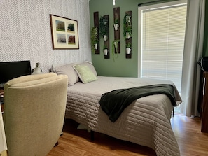 Cozy retreat with a large bed, framed artwork, and lush greenery.