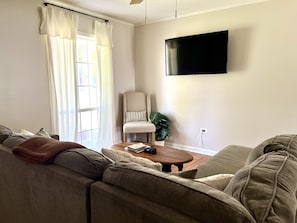 Relax in this stylish living room with a large flat-screen TV, comfortable sofa, and cozy throw blanket.
