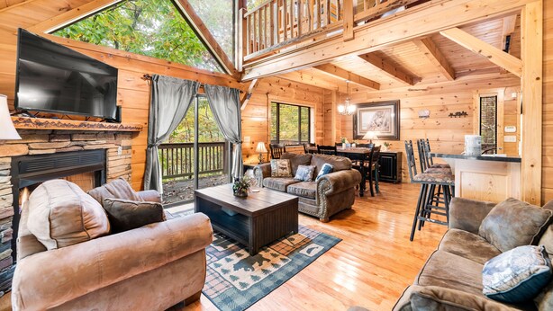 A spacious cabin with a large living area featuring a fireplace, multiple seating options, a dining area, and a kitchen. - Experience serenity near adventure!just an 8-min drive to Top Places.  (Sevierville)