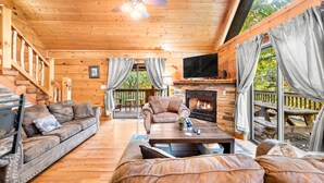 A cozy cabin interior with a wooden ceiling, a fireplace, a sofa, a coffee table, and a TV. - Experience serenity near adventure!just an 8-min drive to Top Places.  (Sevierville)