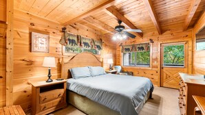 A wooden cabin bedroom with a bed, nightstands, a dresser, and a ceiling fan. - Experience serenity near adventure!just an 8-min drive to Top Places.  (Sevierville)