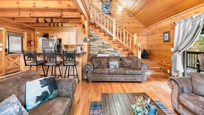 A wooden cabin interior with a dining area, a sofa, a staircase, and a kitchen. - Experience serenity near adventure!just an 8-min drive to Top Places.  (Sevierville)