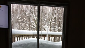 Una habitación con un amplio ventanal que da a una terraza cubierta de nieve.