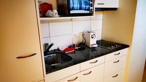 Una cocina con armarios blancos, una encimera negra, un microondas y una cafetera.