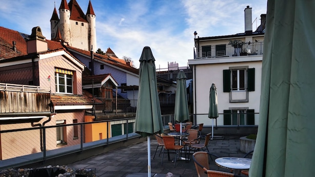 Una terraza con mobiliario exterior, un hogar de piedra y vistas a un edificio parecido a un castillo al fondo.
