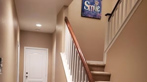 Ein Teppich ausgelegter Flur, der zu einer Treppe mit einer weißen Tür am Ende führt.