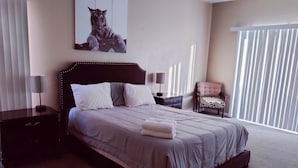 Ein Schlafzimmer mit einem großen Bett, einem Nachttisch, einem Sessel, einer Lampe und einem Tigerbild an der Wand.