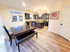 Une cuisine moderne avec des meubles de couleur sombre, un îlot central et un coin repas doté d’une banquette.