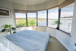 A bedroom with a large bed, a view of a marina with boats, and a plant on the windowsill. -     Luxury Waterfront Penthouse in Cronulla (Burraneer)