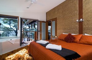 Um quarto moderno com uma cama grande, vista por uma porta de vidro e um ventilador de teto.